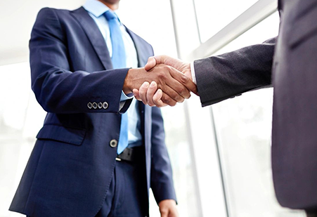 Two men in suits shaking hands over a window.